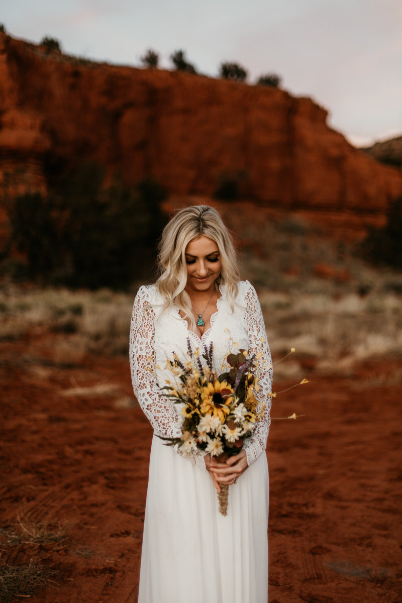 bride holding bouquet surrounded by red rocks