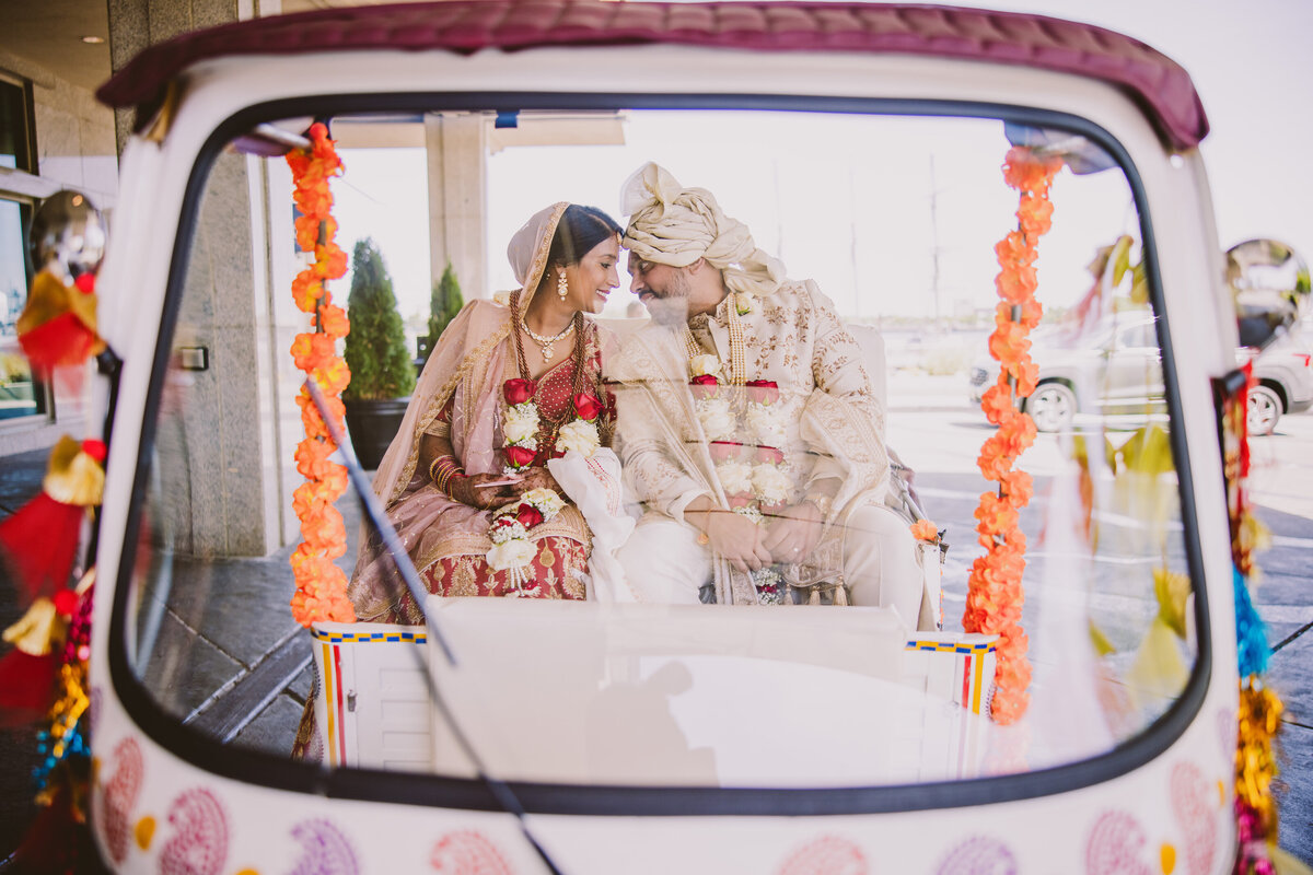 Indian bride and groom touch foreheads inside a decorated auto riksha tuk-tuk after their hindu ceremony at hilton penn's landing philadelphia