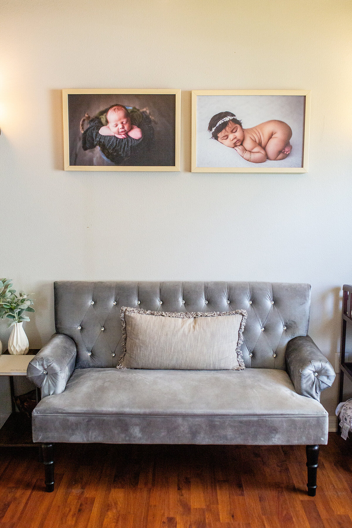 Grey couch in client lounge and hanging canvas artwork showcasing the newborn portraits