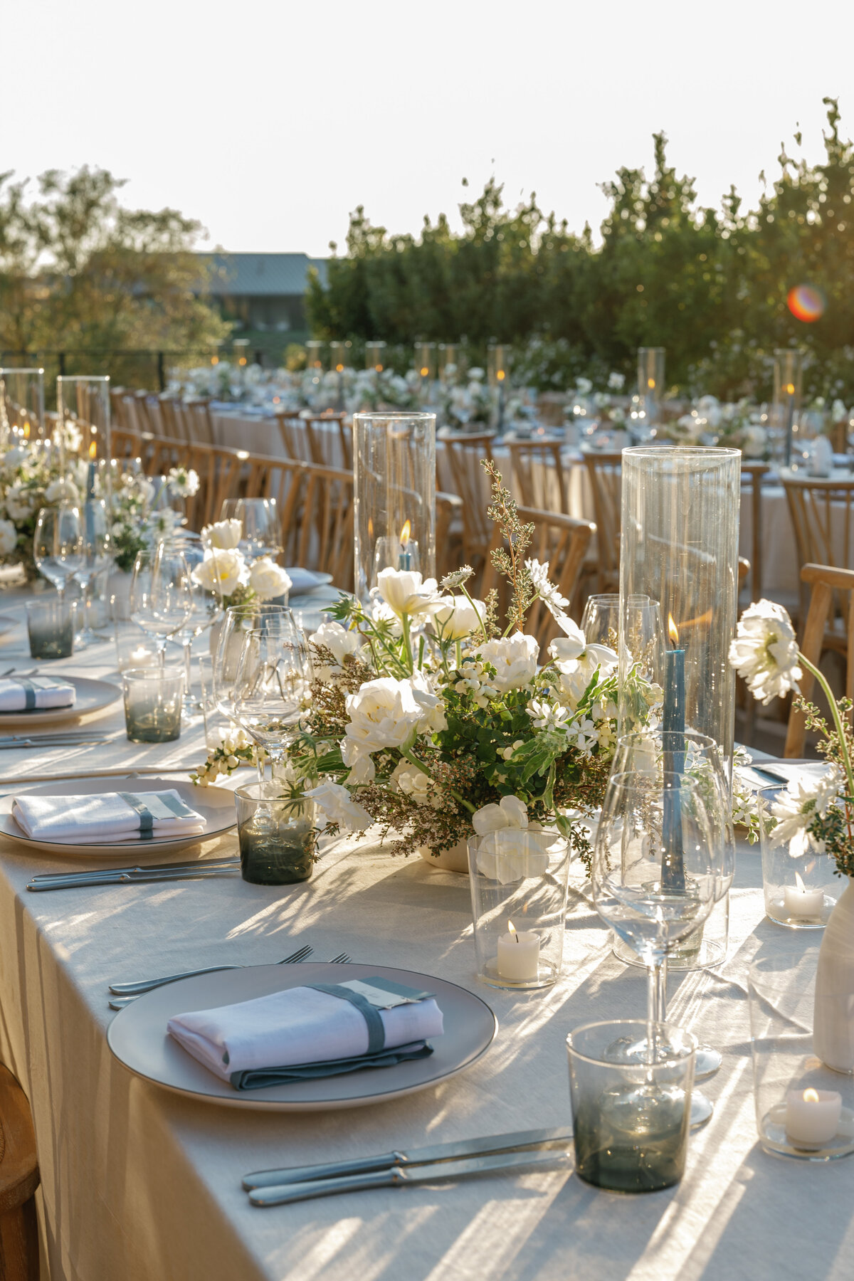 modern and neutral table  design with heath ceramic stoneware, theoni rentals linens and clean and minimal flower arrangements and blue taper candles.