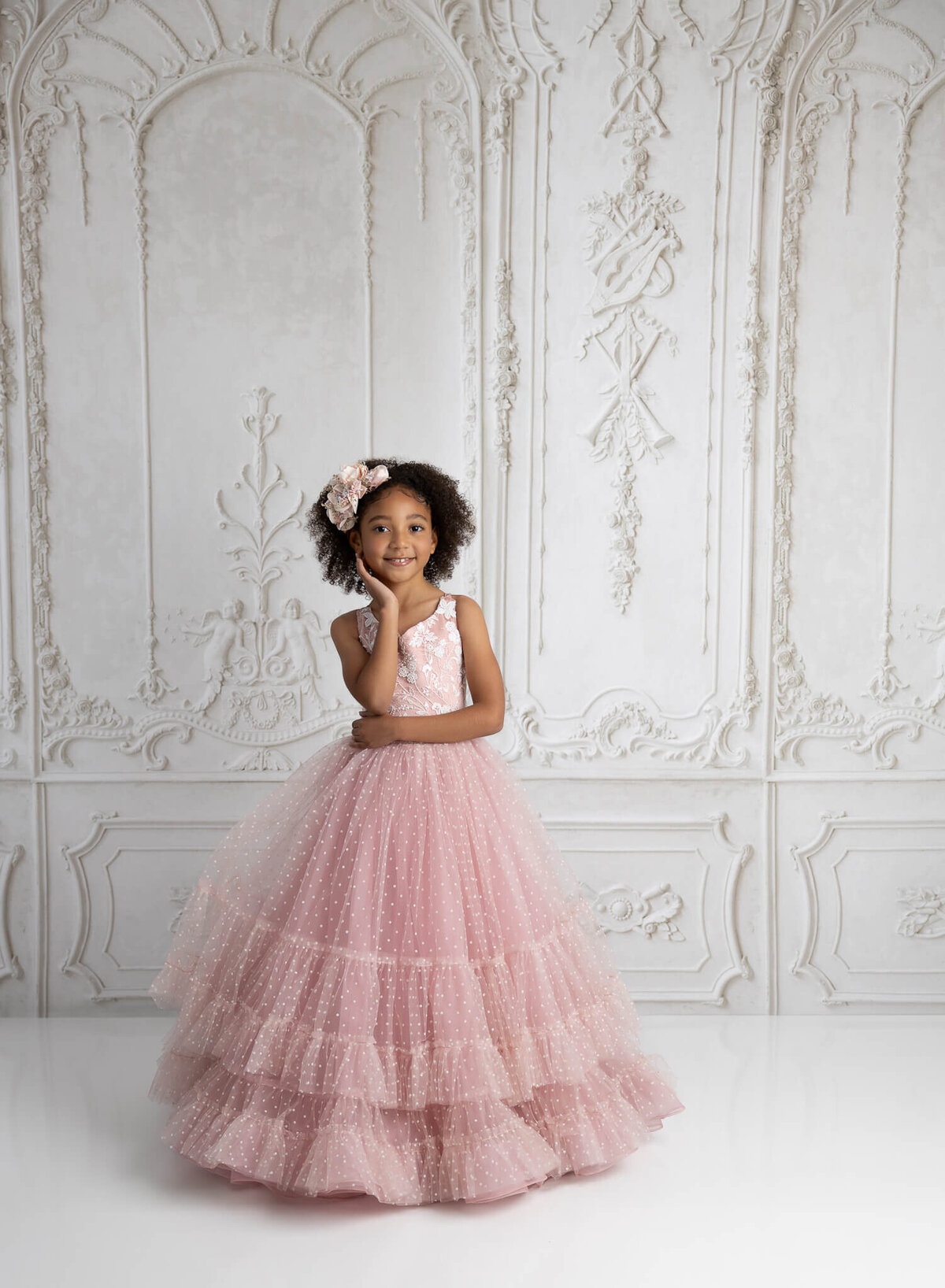 Young girl with posed hands and big smile in pink tulle dress