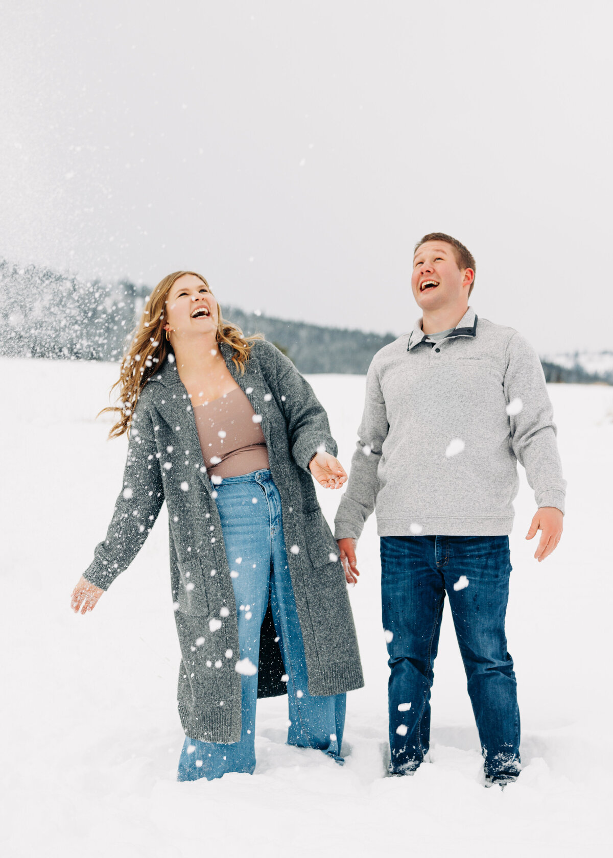 Winter engagement photo couple playing in snow at Blue Mountain in Missoula