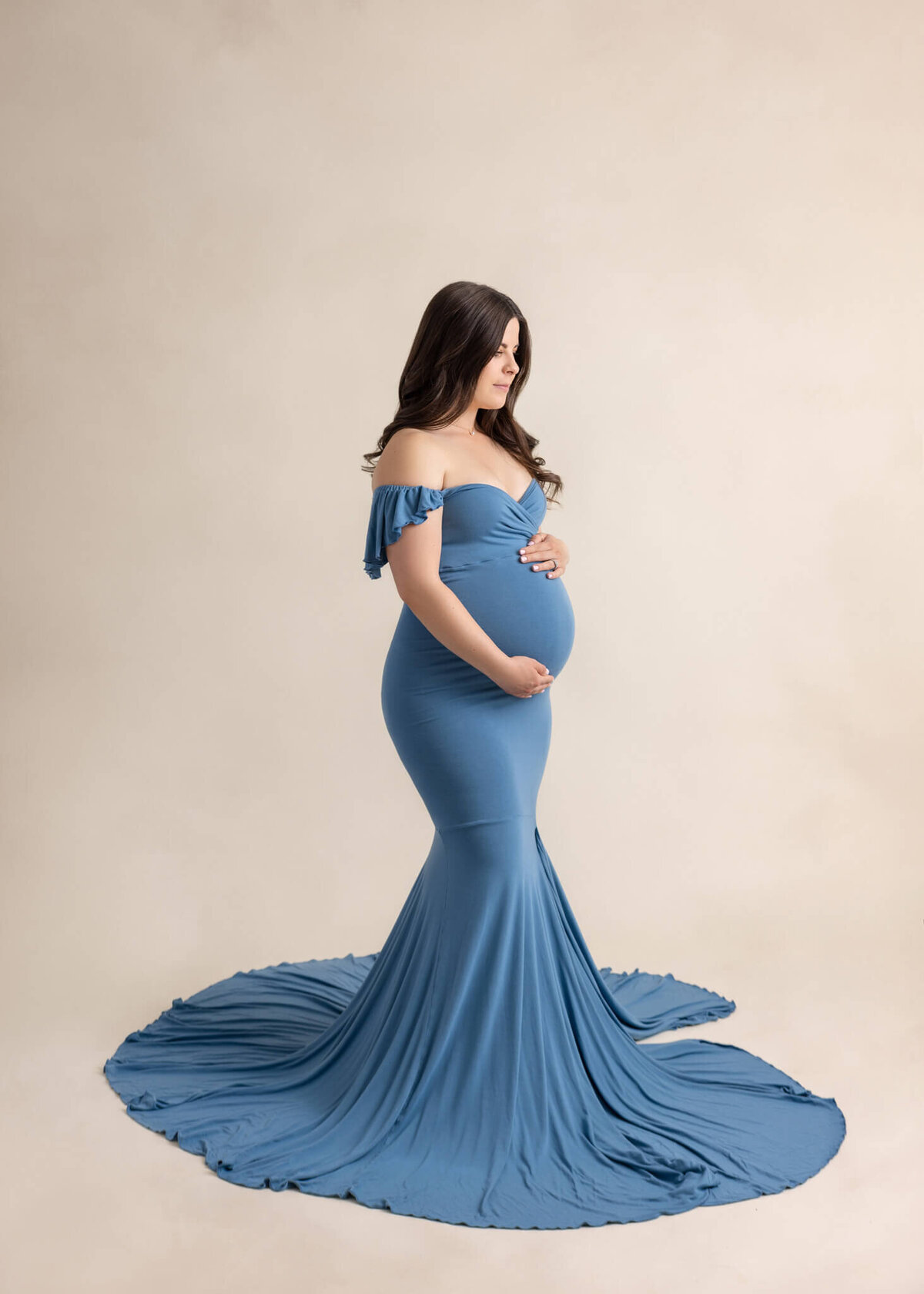 expectant mom in a blue dress cradling her belly