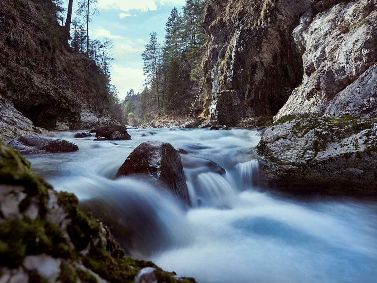 Dynamischer Gebirgsbach fließt durch eine felsige Waldschlucht Schlitza – Langzeitbelichtung mit natürlicher Farbgebung für stimmungsvolle Landschaftsfotografie