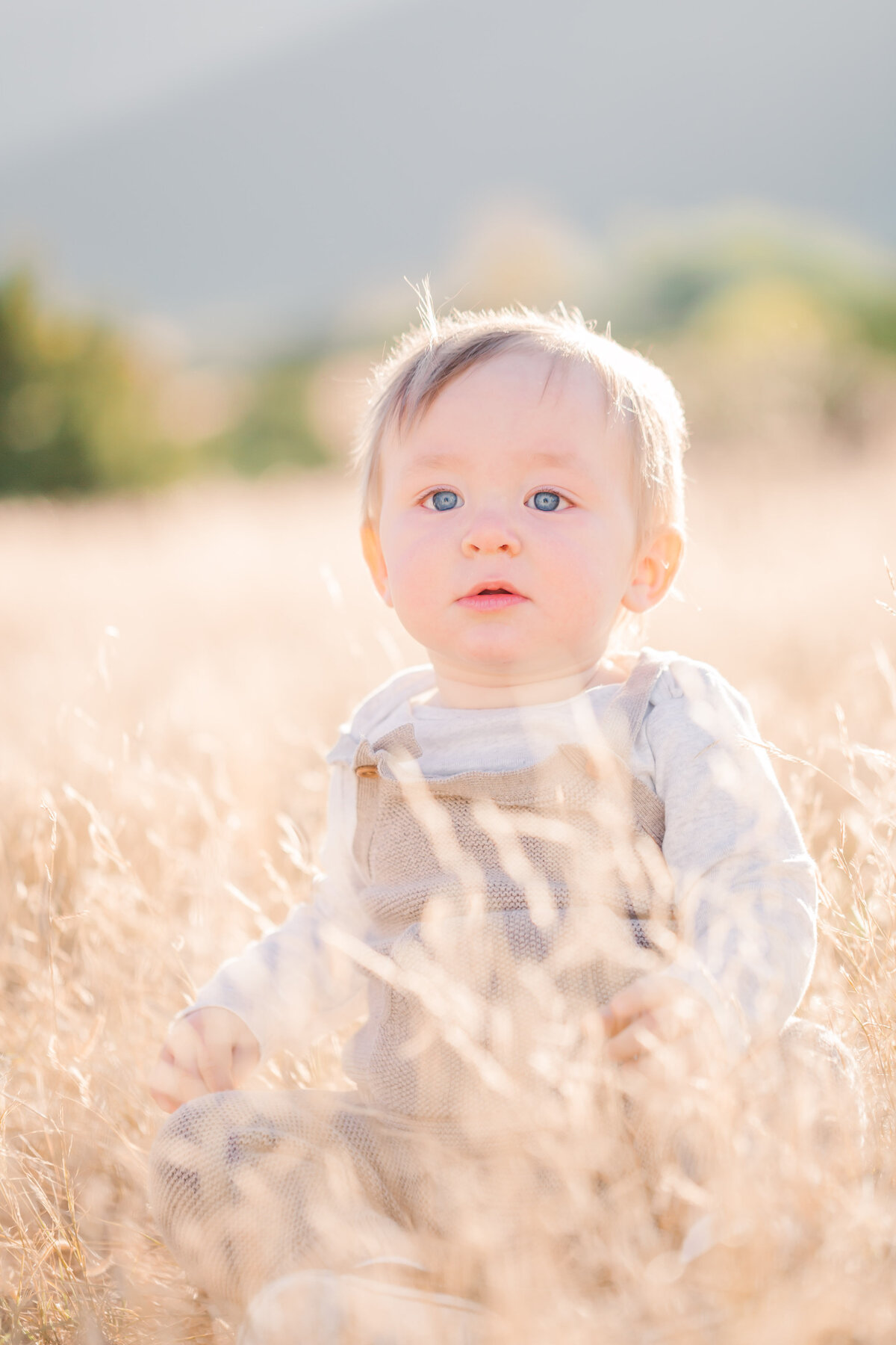 Baby boy with big blue eyes sitting in a field