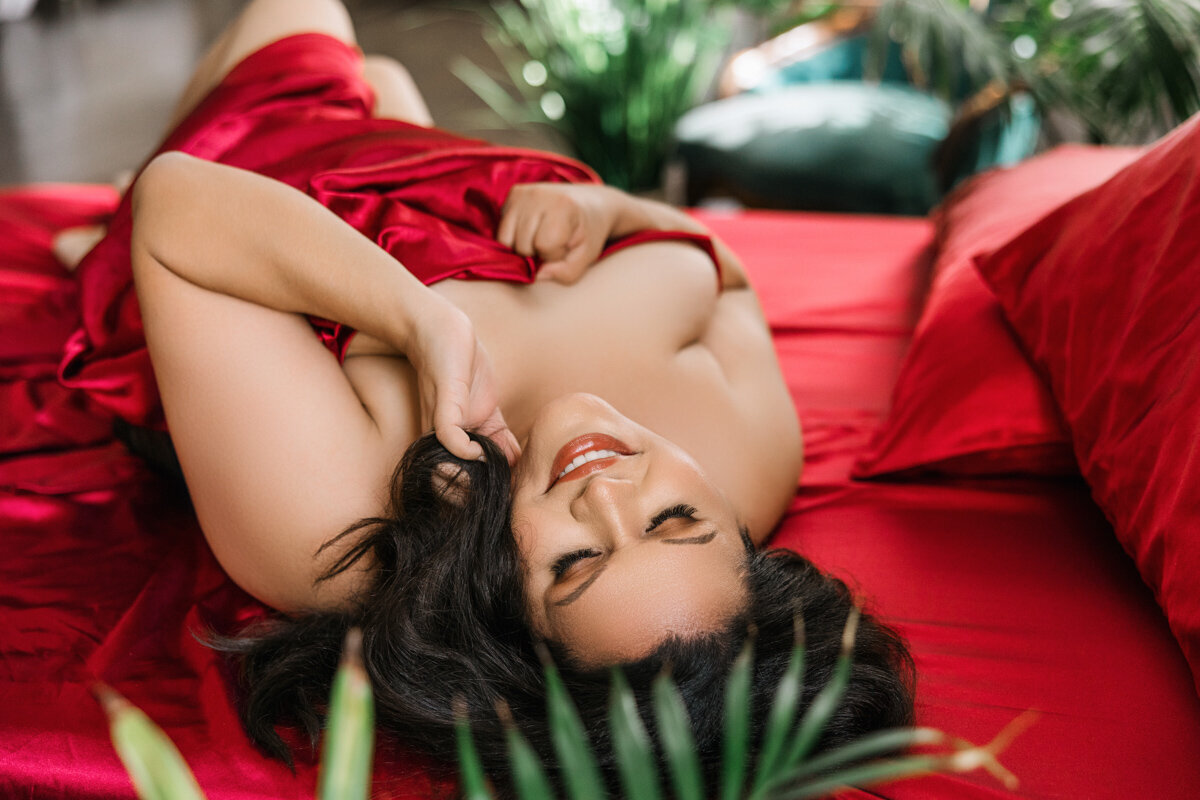 woman smiling wrapped in red bed sheets