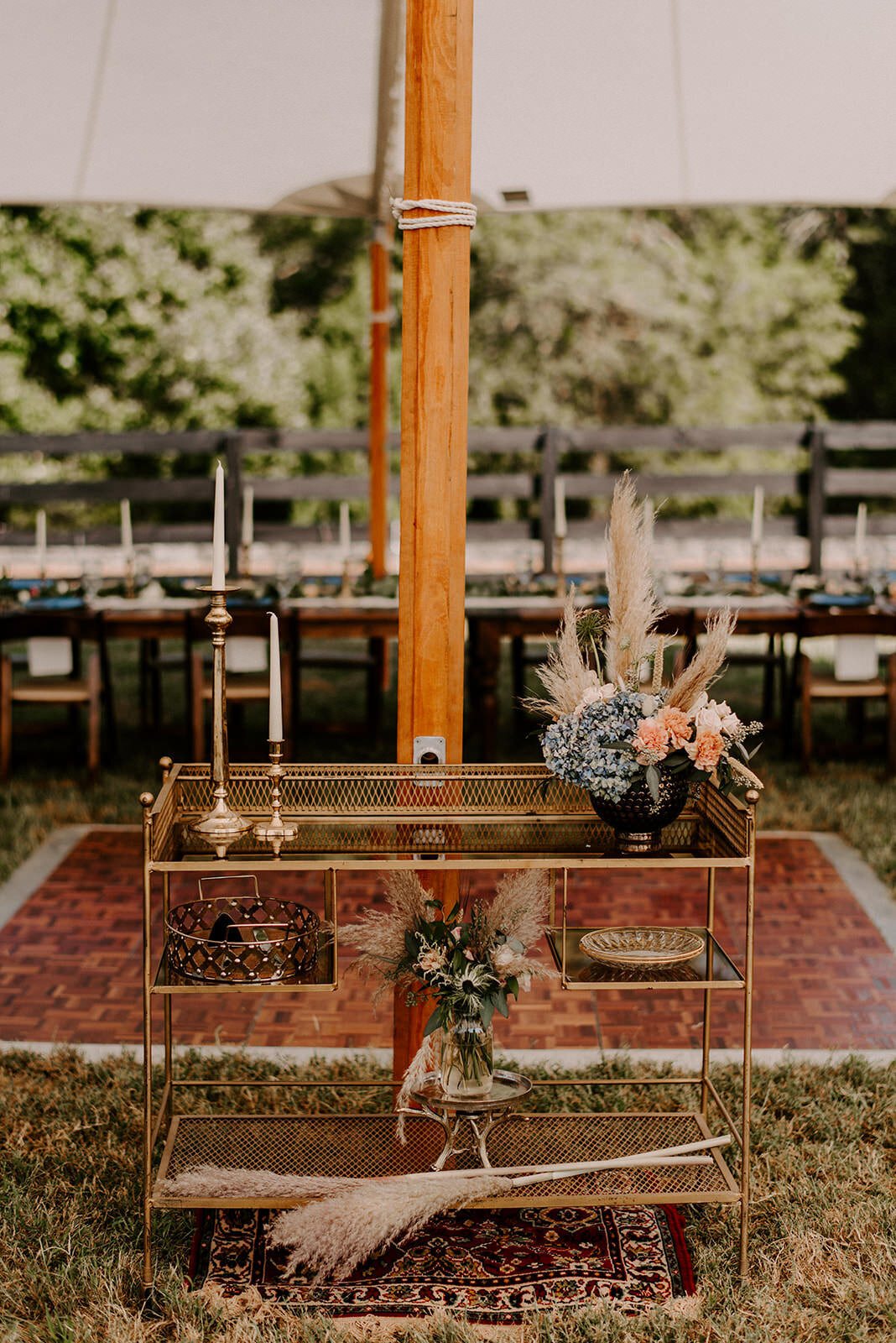 welcome boho cart with arrangement, pampas, blue hydrangea and dance floor in the background