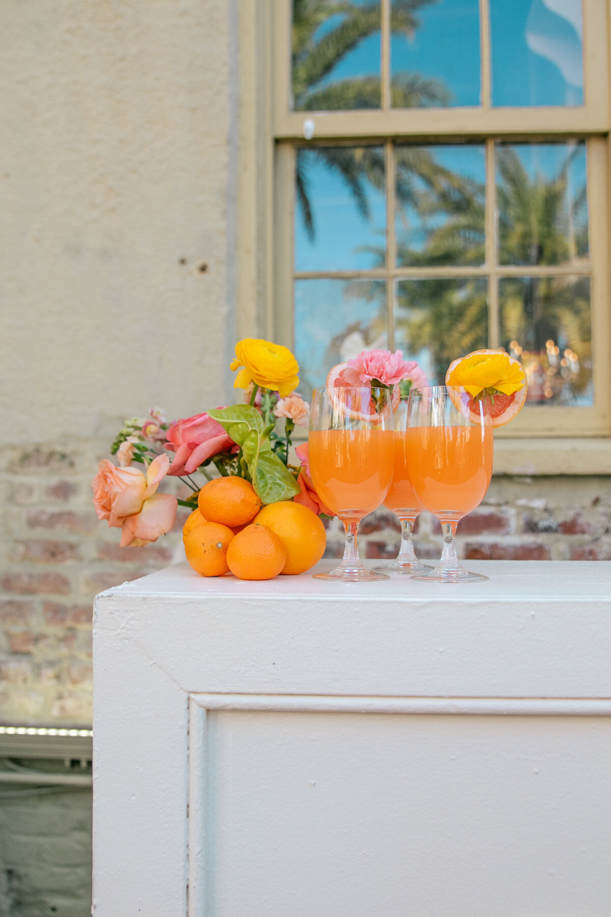 Orange Cocktails with florals on a white bar