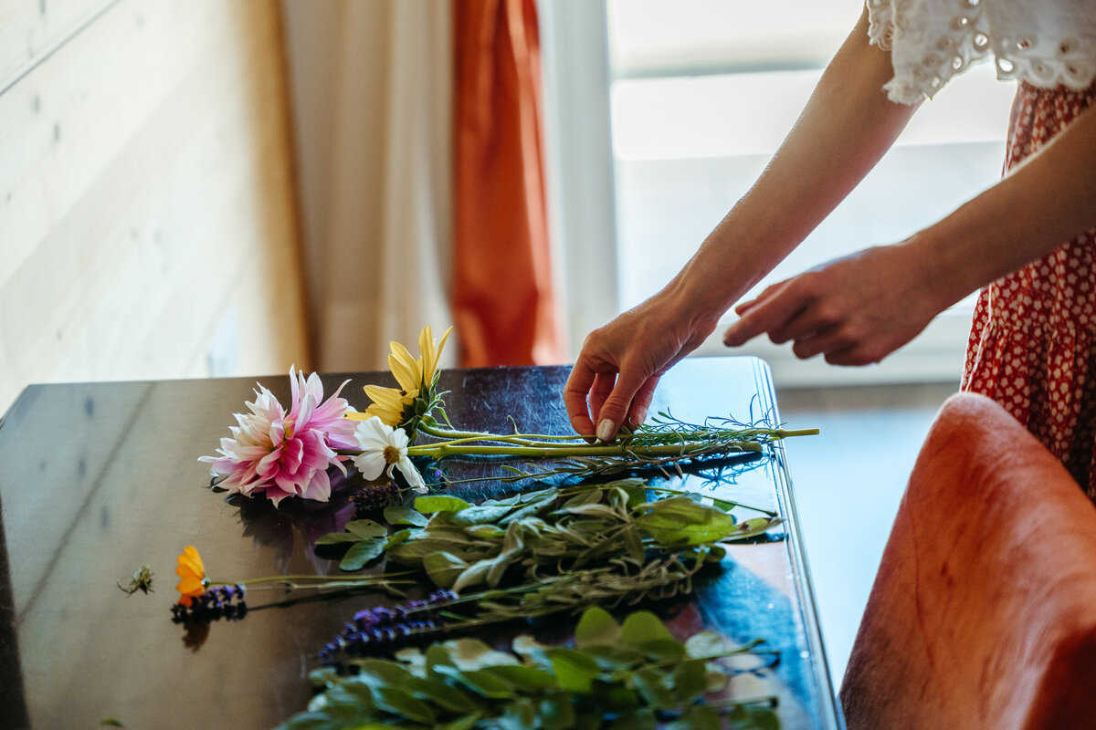 Bride laying flowers on table while arranging bouquet