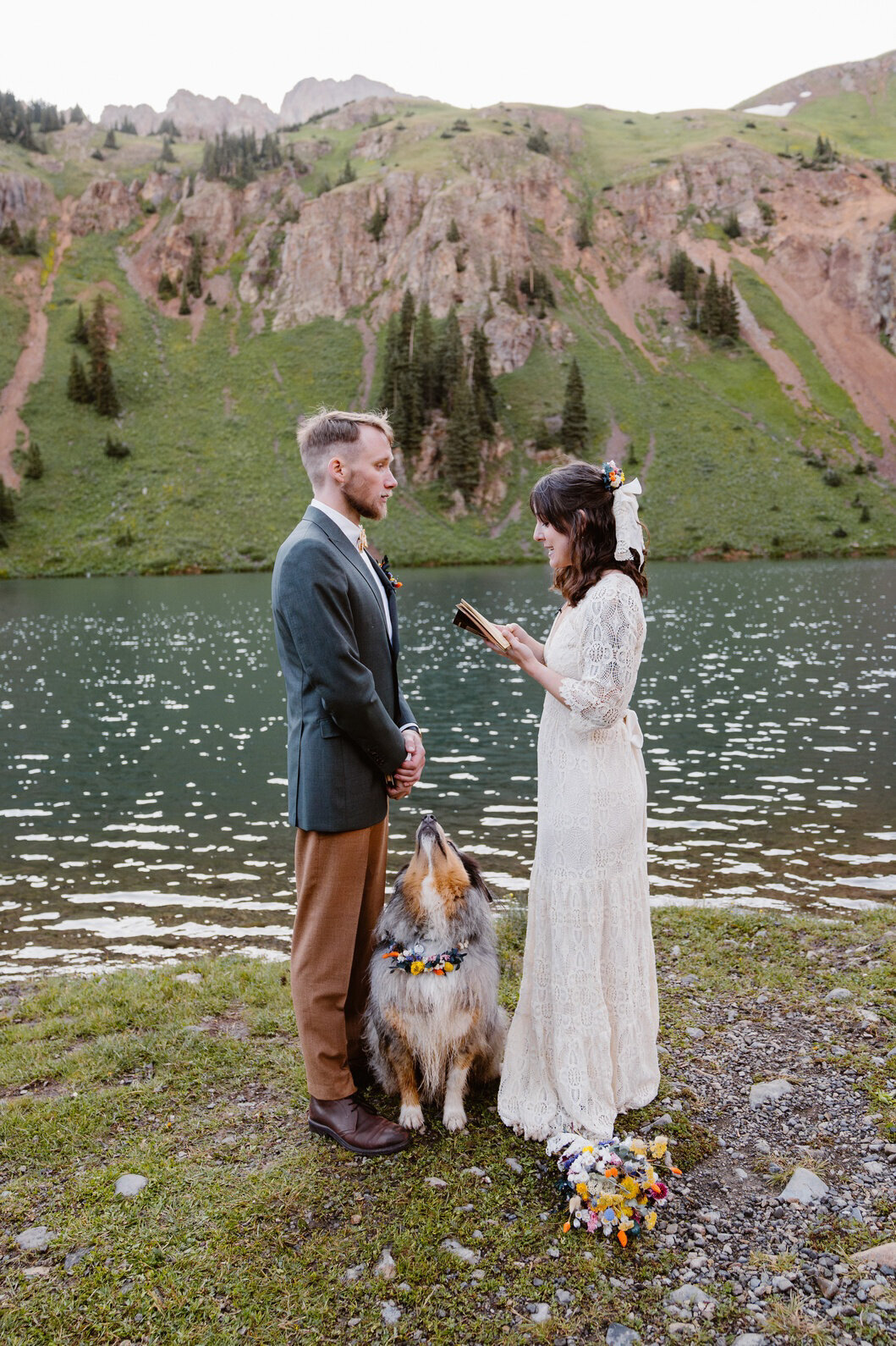 Couple stands beside the turquoise waters of Blue Lakes surrounded by rugged peaks in Ridgway, Colorado.