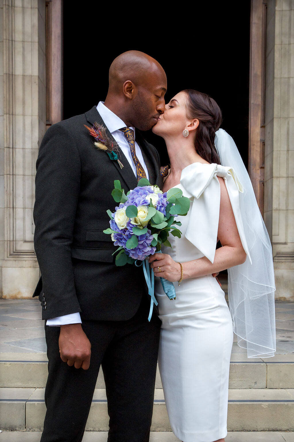 Bride and groom kiss.  Bride has lilac bouquet