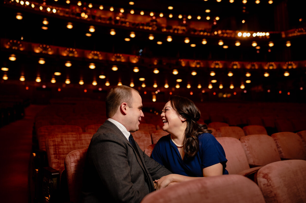 A couple look at each other in a theater.