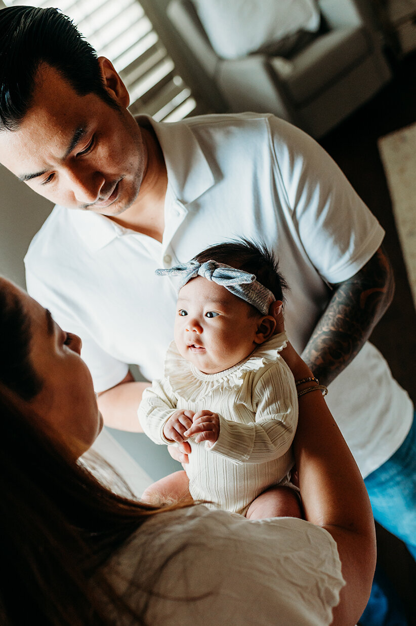 Mom and dad holding and looking at baby girl