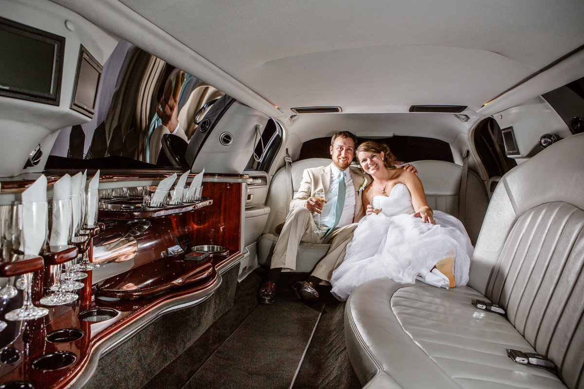 The new couple poses in the back of a limousine before leaving the wedding reception.