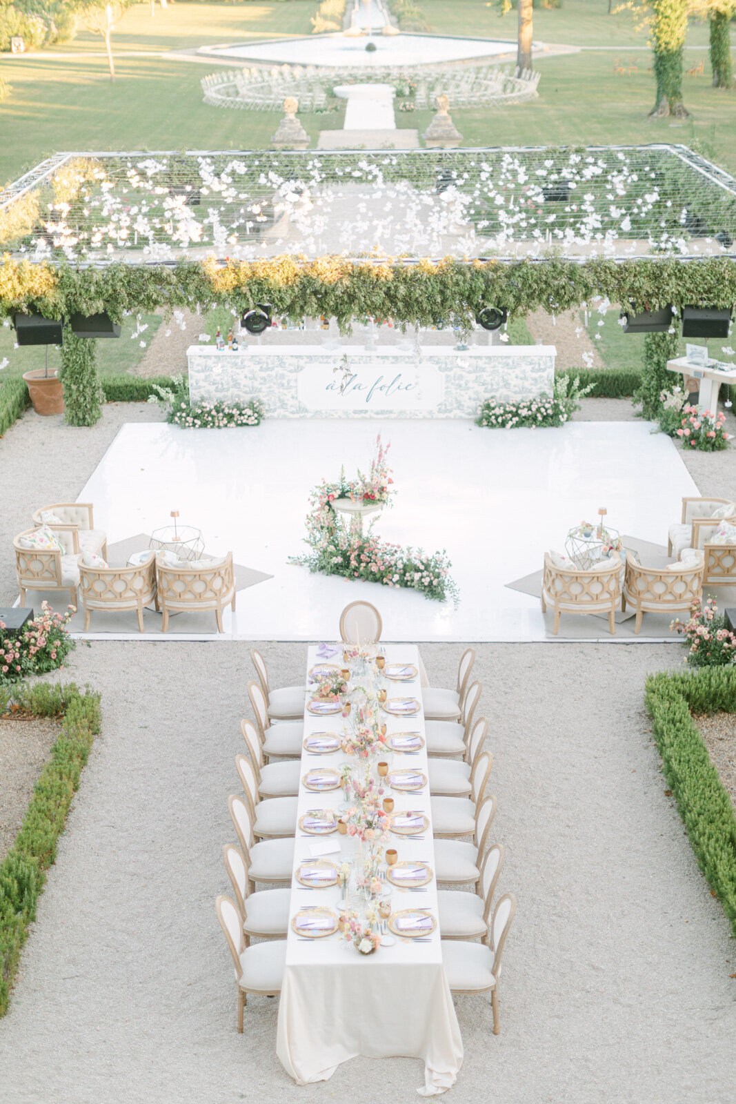 Elegant outdoor wedding setup in Provence château with dinner tables, floral bar, and dance floor.