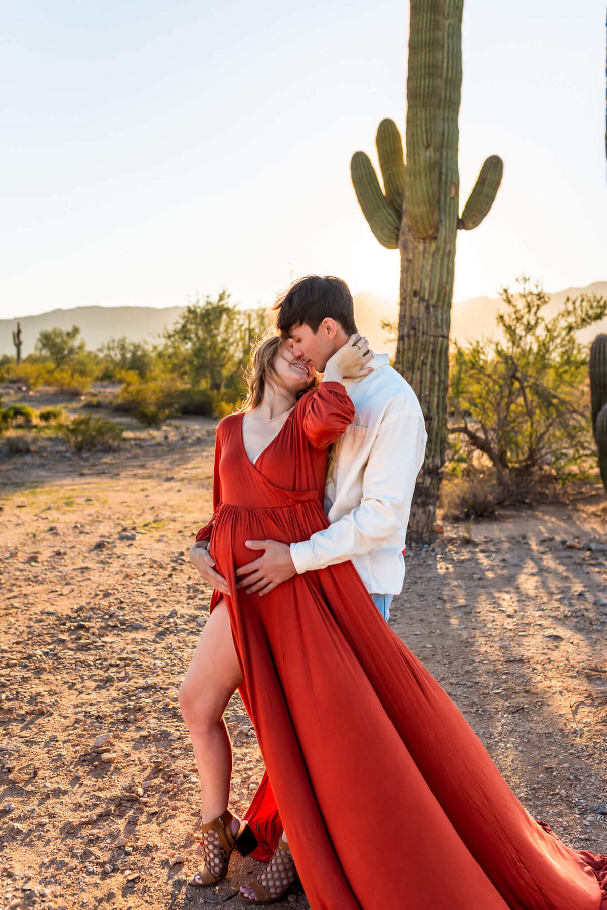 Expecting parents sharing a gentle kiss in Arizona desert.