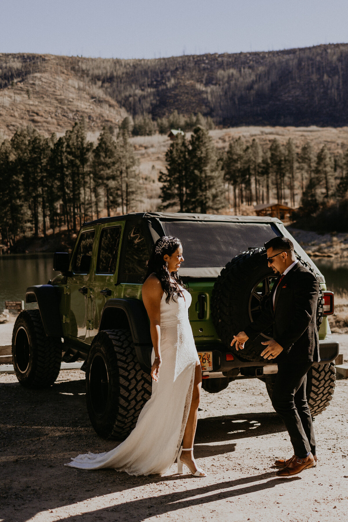 bride adn groom having a first look around the sides of their jeep wrangler