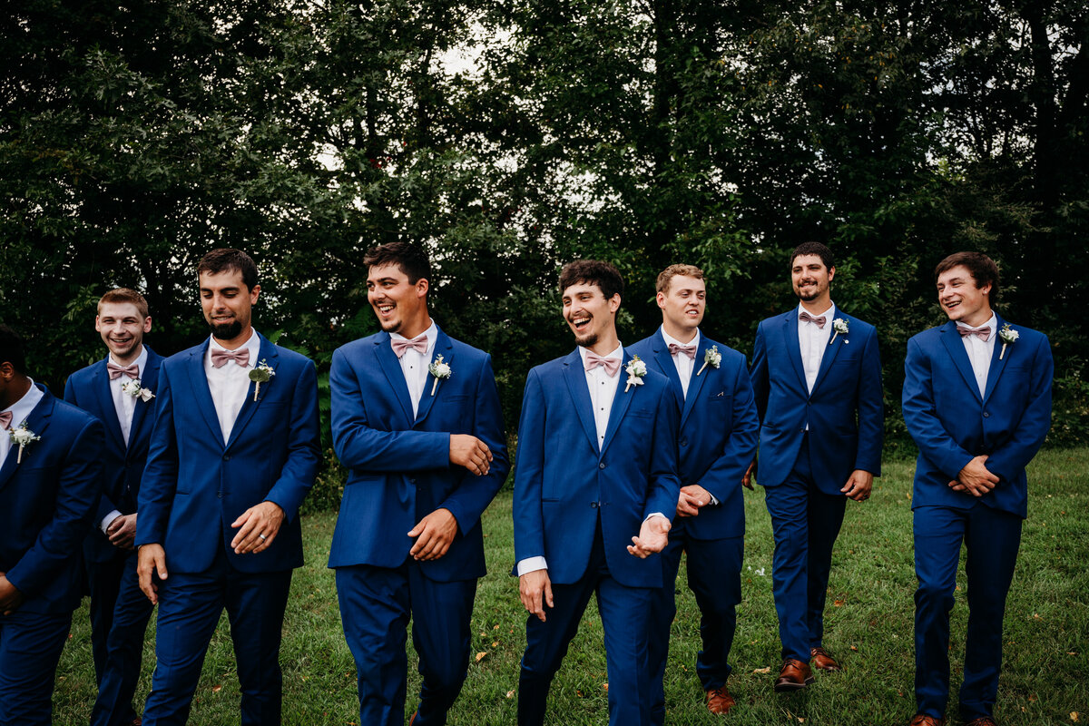 Grooms and groomsmen laughing and walking