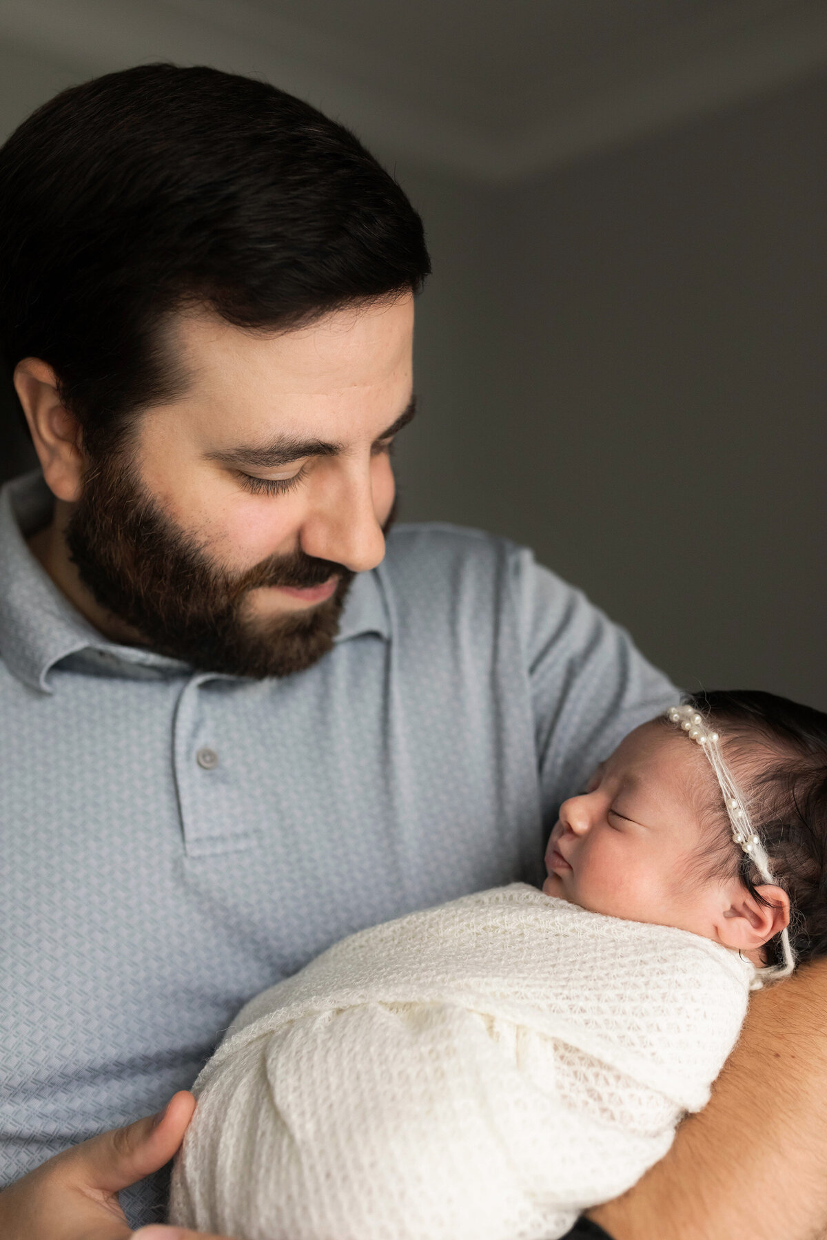 NJ Newborn Photographer poses dad as he looks at his little girl
