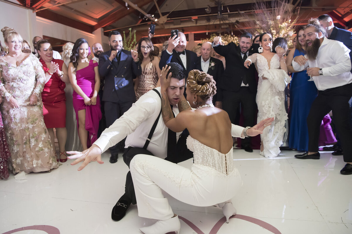 Two people squatting down and dancing together at a wedding reception 