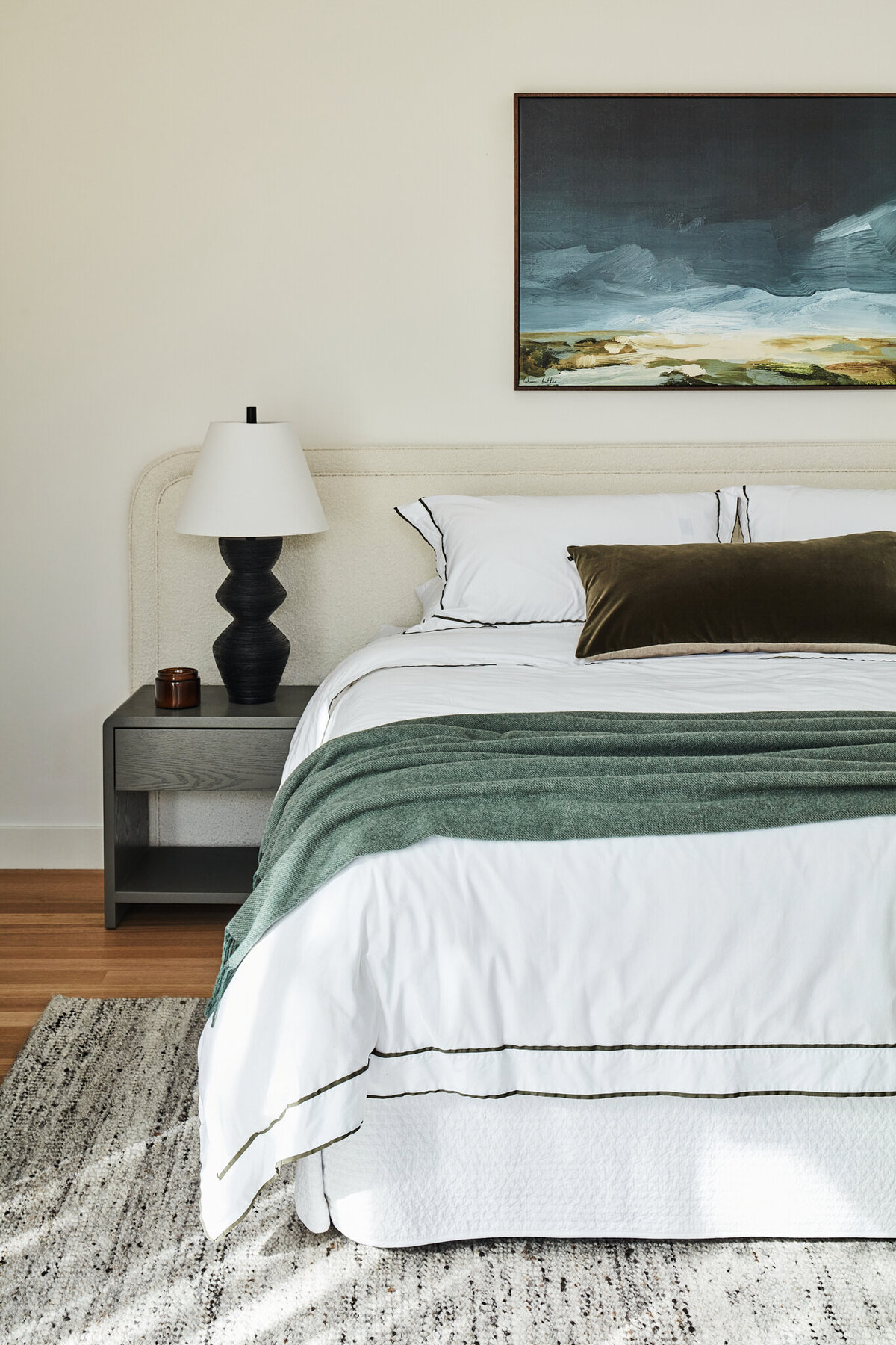 Melbourne interior decorator bedroom styling with upholstered bedhead, layered bedding, bedside lamp, and artwork.