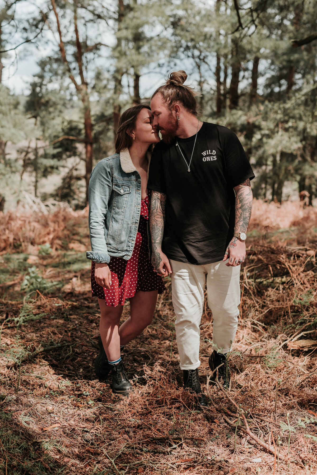Man and woman walk gently holding hands close to eachother, along a wooded pathway in the New Forest