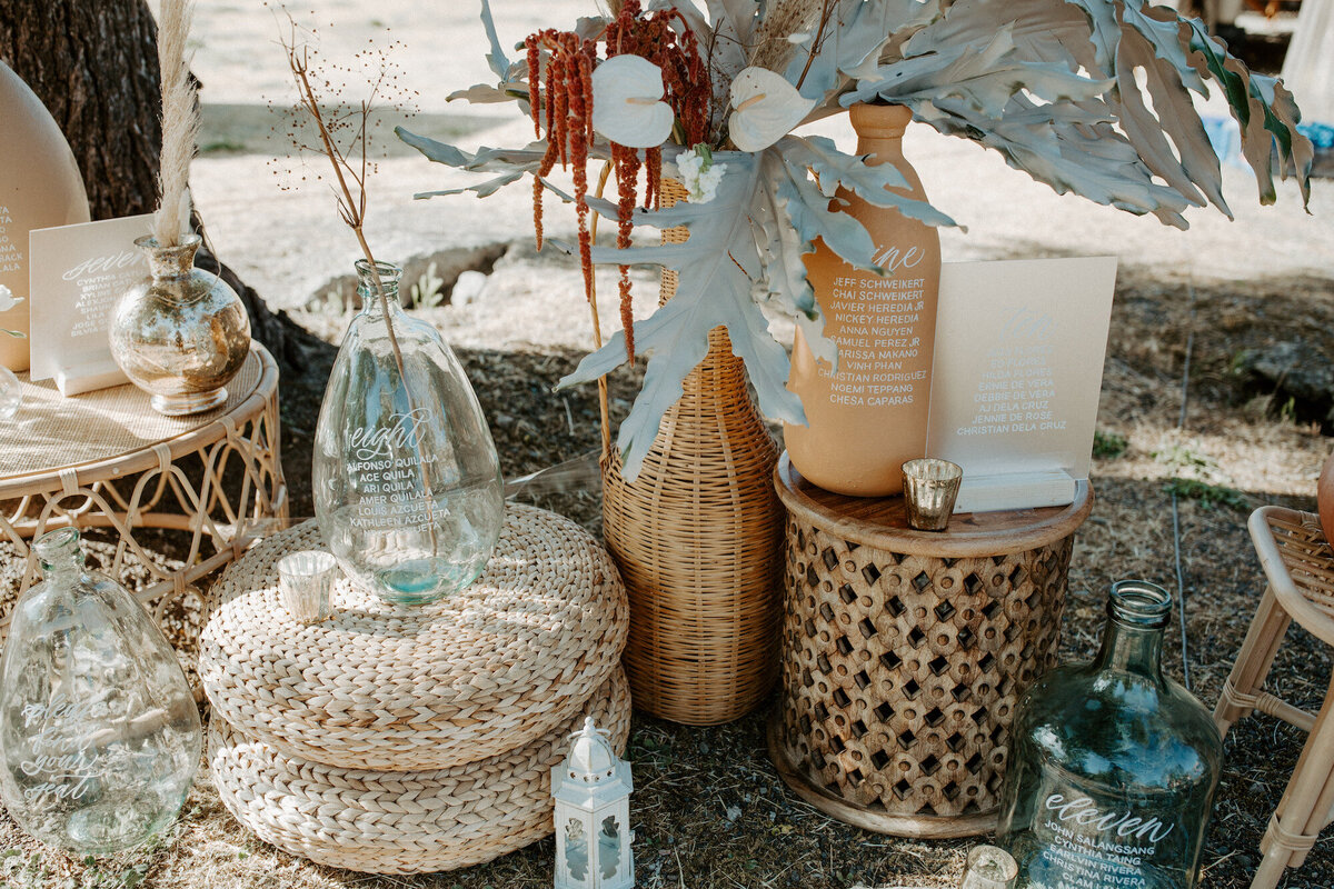 Seating chart display using glass jug sand terra cotta jars, decorated with dried florals for a ranch wedding