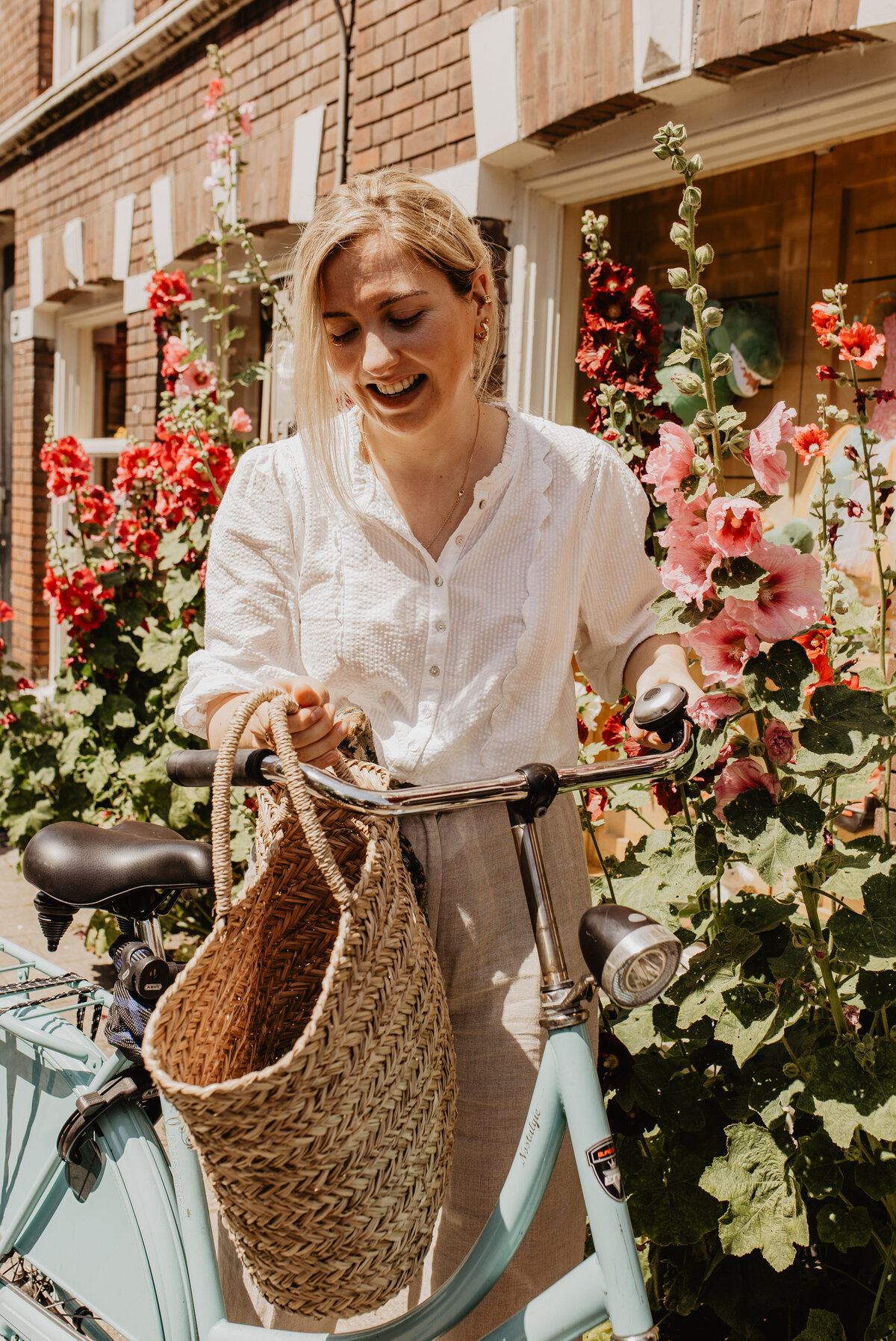 Pernille Hansum voor website PERLE met blauwe fiets en rieten tas