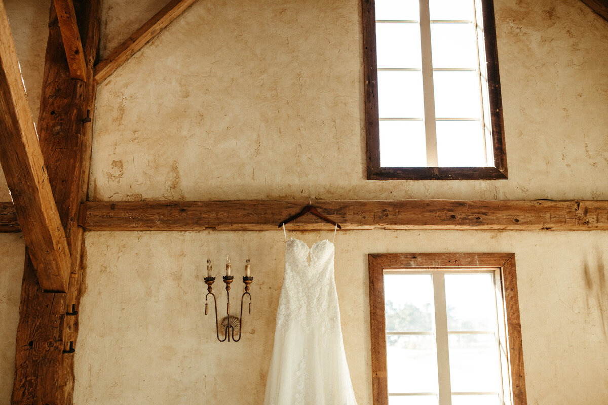 Strapless wedding dress hanging up inside venue with natural light