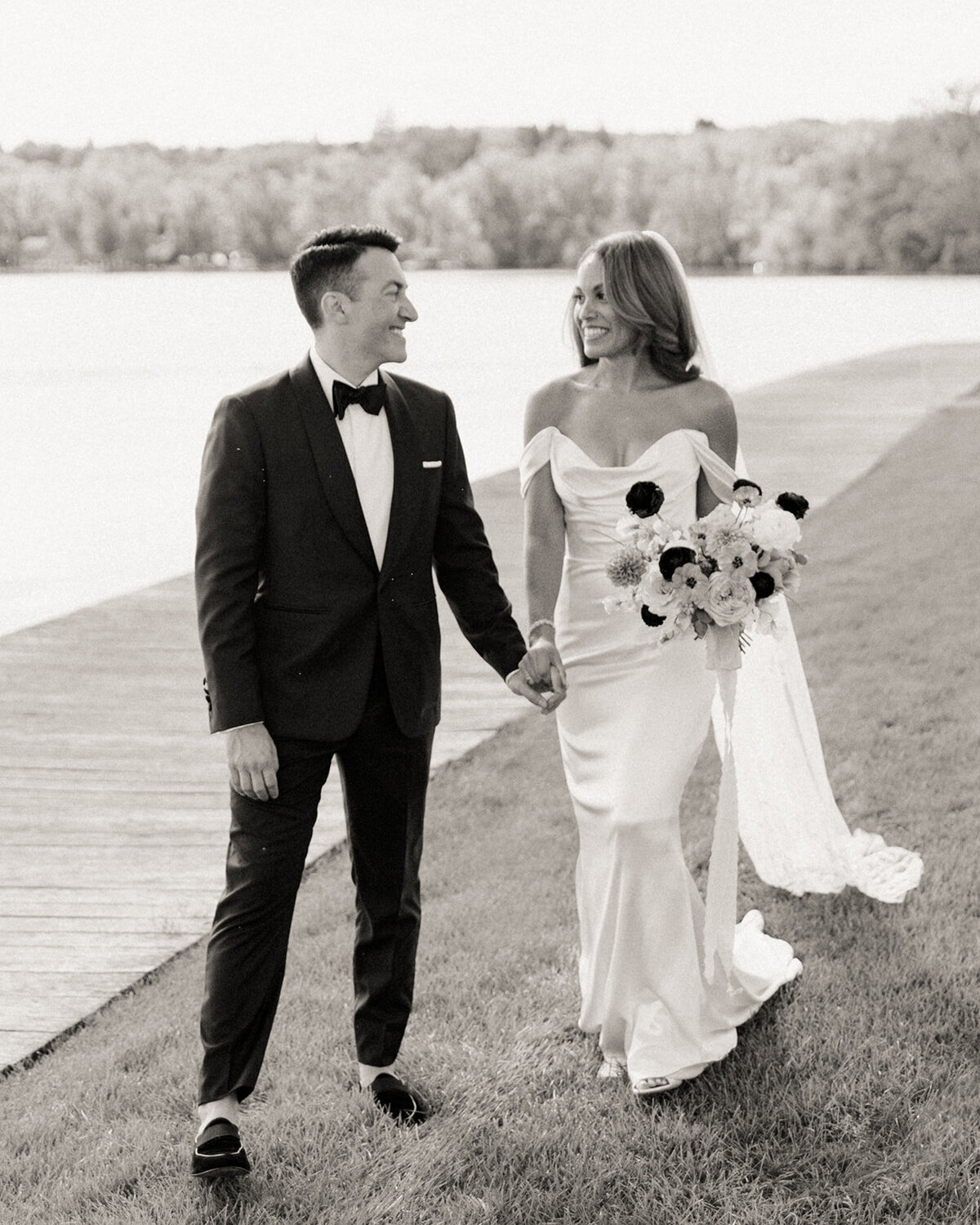 The wedding couple takes a walk by the water at The Lake House on Canandaigua