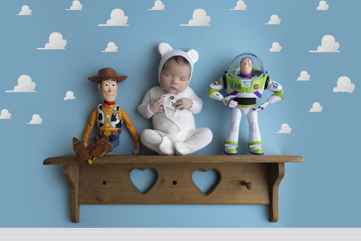 A newborn sits on a shelf with toys from the Pixar movie Toy Story, captured in St. Louis Missouri.