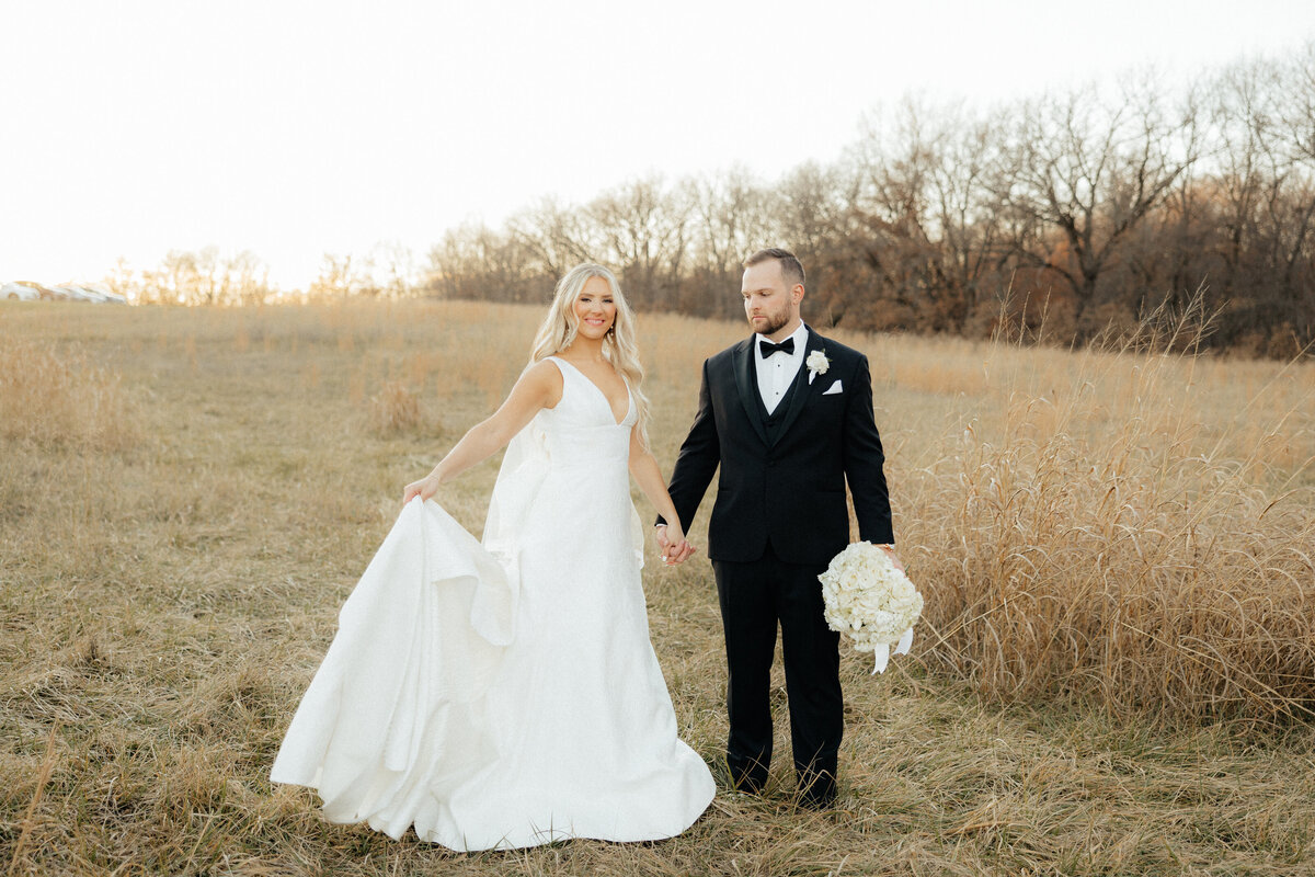 The bride and groom looking at each other in a field.