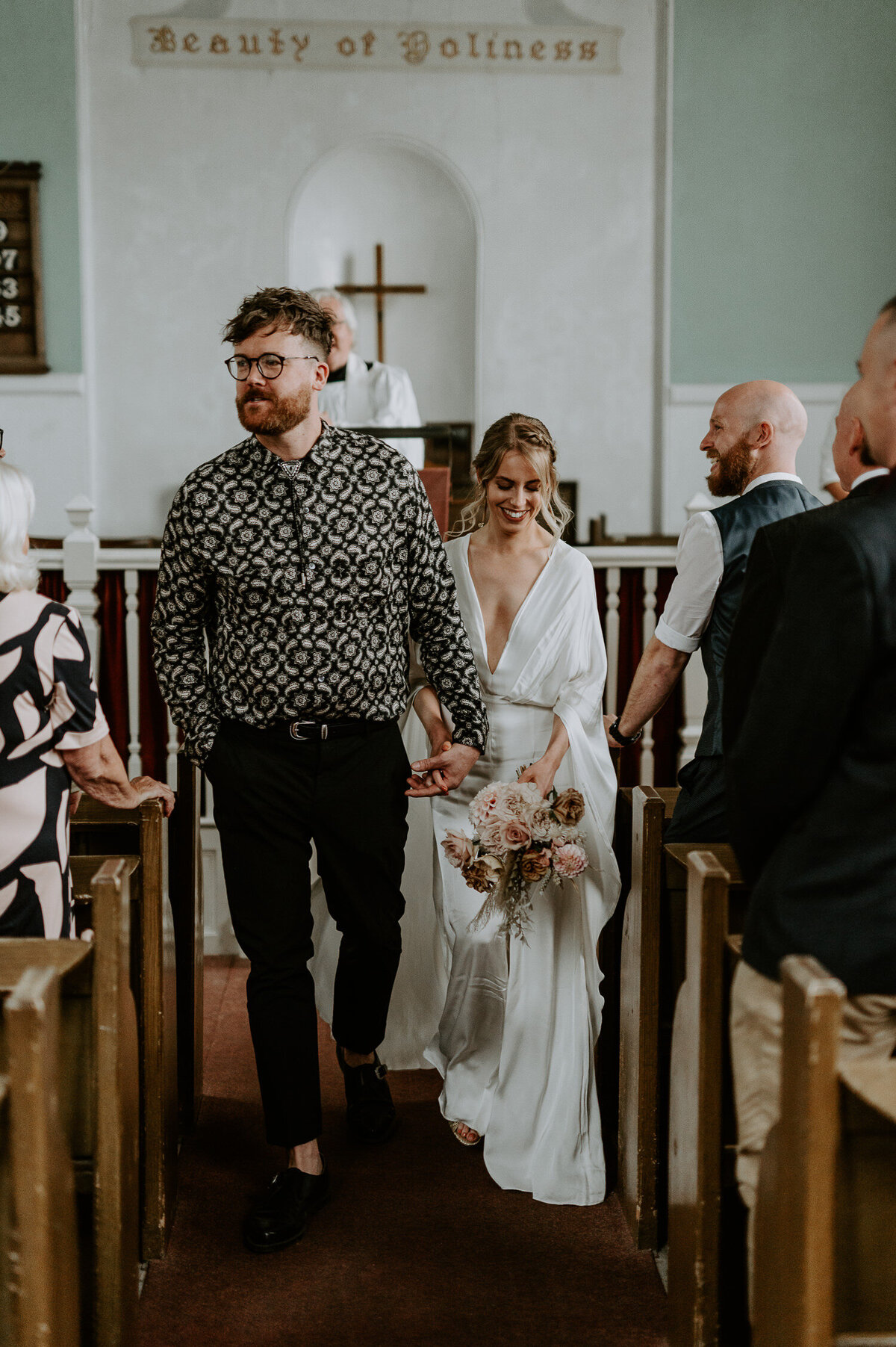 A bride and groom exit their small church wedding in Bristol. The church is small and decaying, it reminds me of a Little White Chapel Las Vegas wedding church. The couples wedding was a boho themed.
