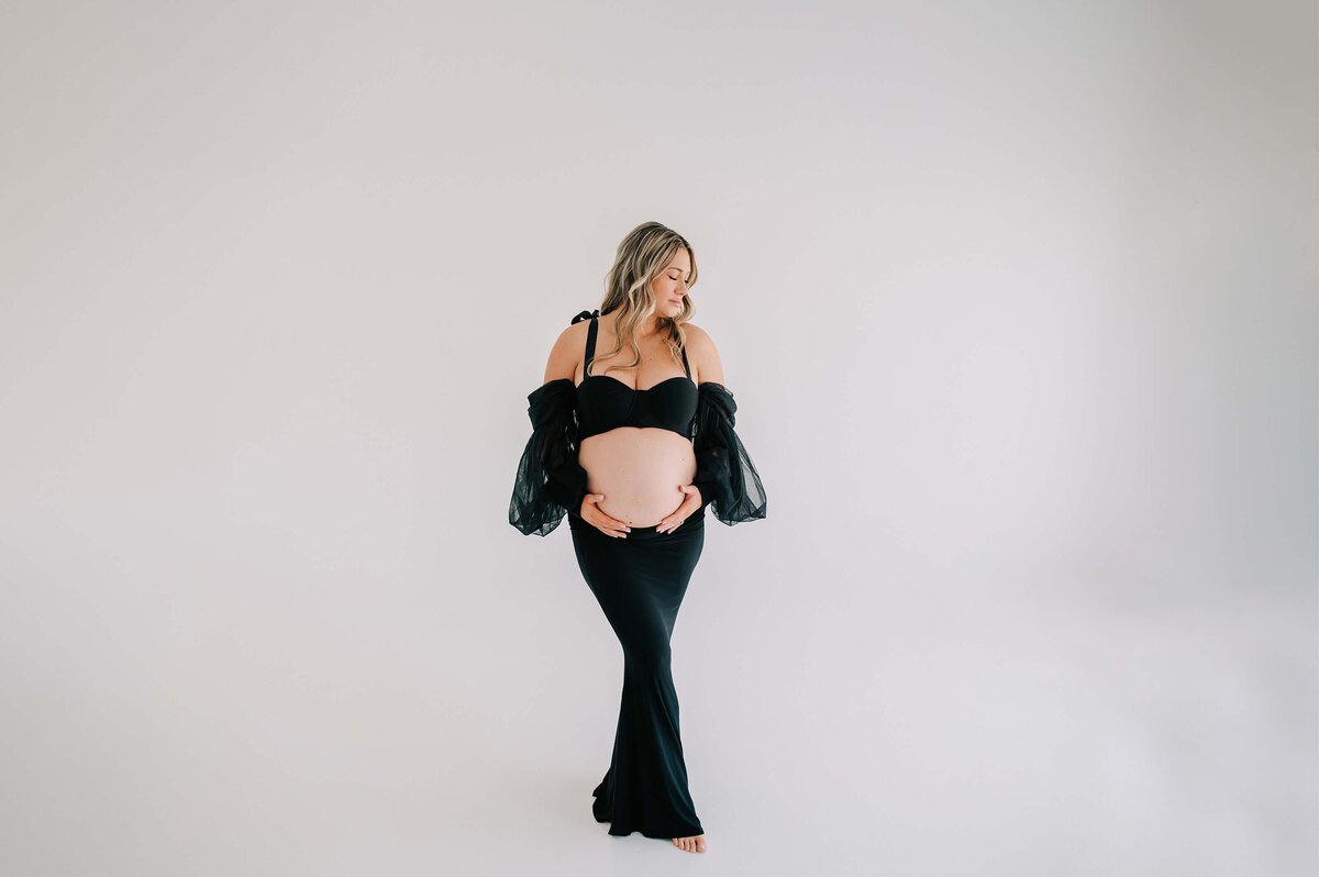 maternity picture in Branson MO of pregnant mom in black dress holding baby bump
