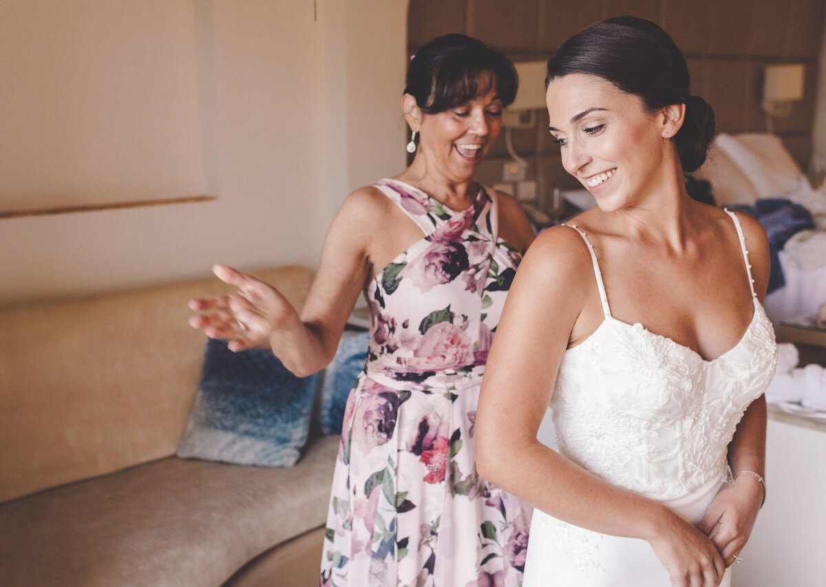 Mom helping bride into dress before wedding in Riviera Maya