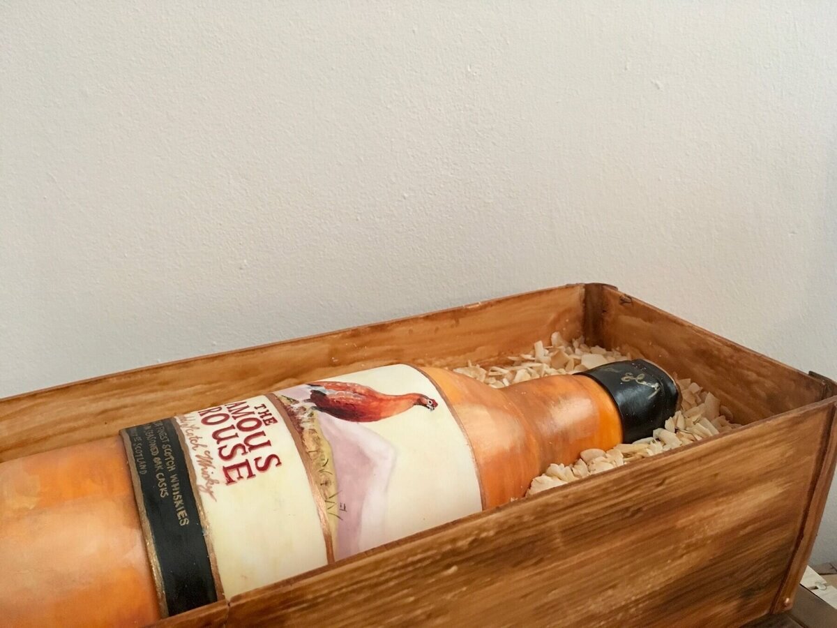 A cake in the shape of a bottle of The Famous Grouse in a display box