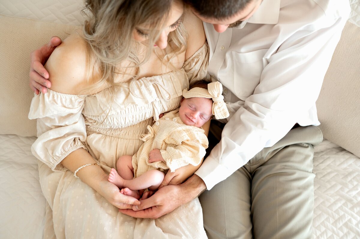 baby smiling while parents hold her in their arms