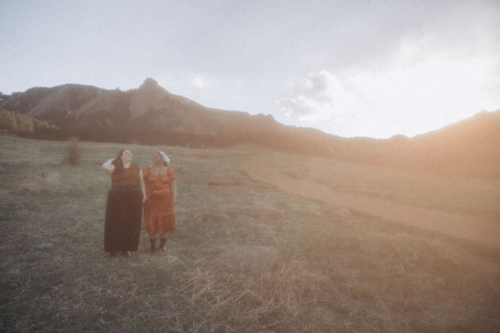 A couple walking in a grassy field together.