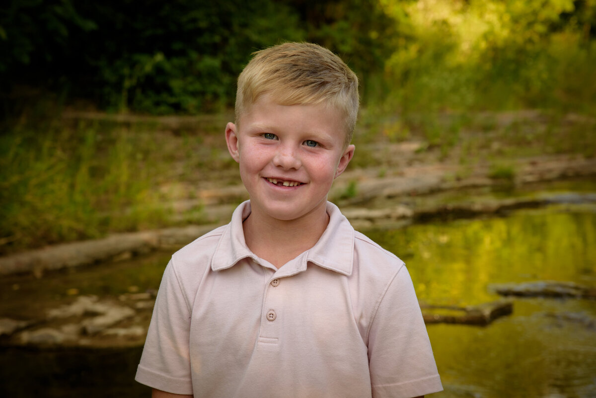 Portrait of young blonde haired boy smiling with a missing tooth at Fonferek Glen County Park near Green Bay, Wisconsin