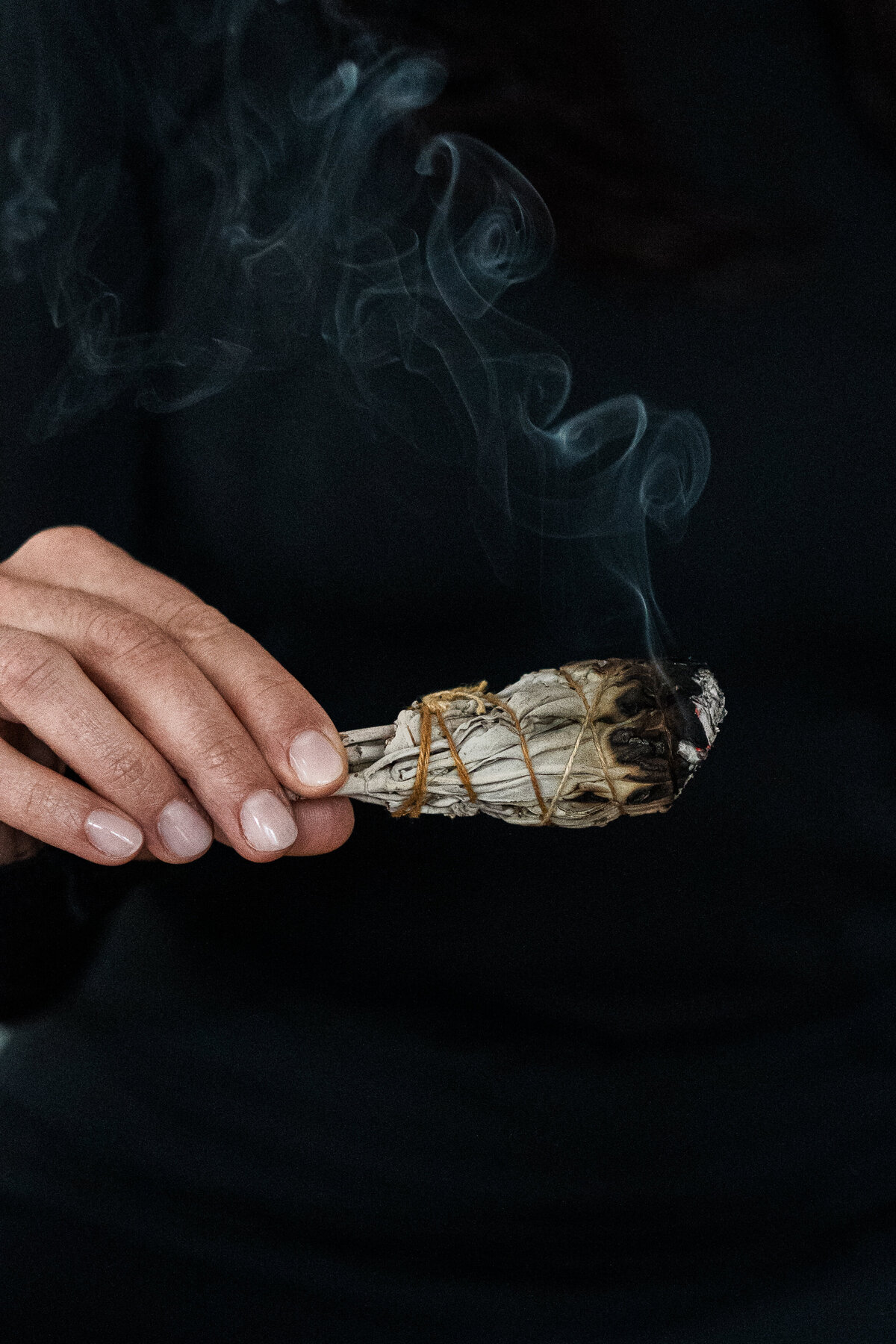 woman's hand holding a bundle of smoldering sage