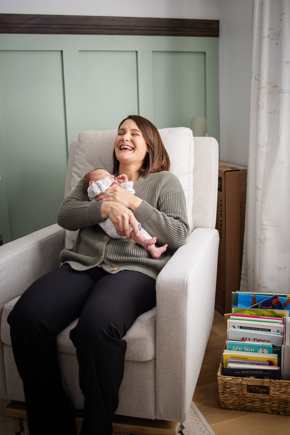 Mom laughing in rocking chair in nursery