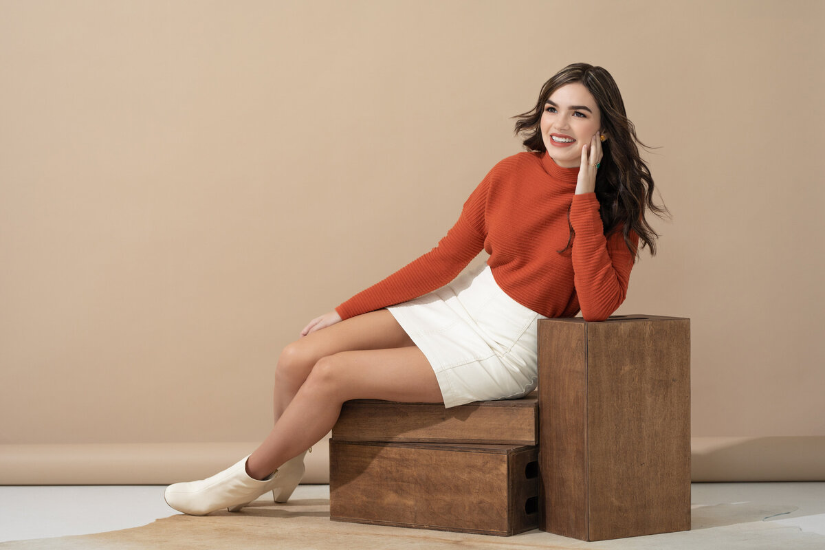 A girl sitting on a box leaning against a round table