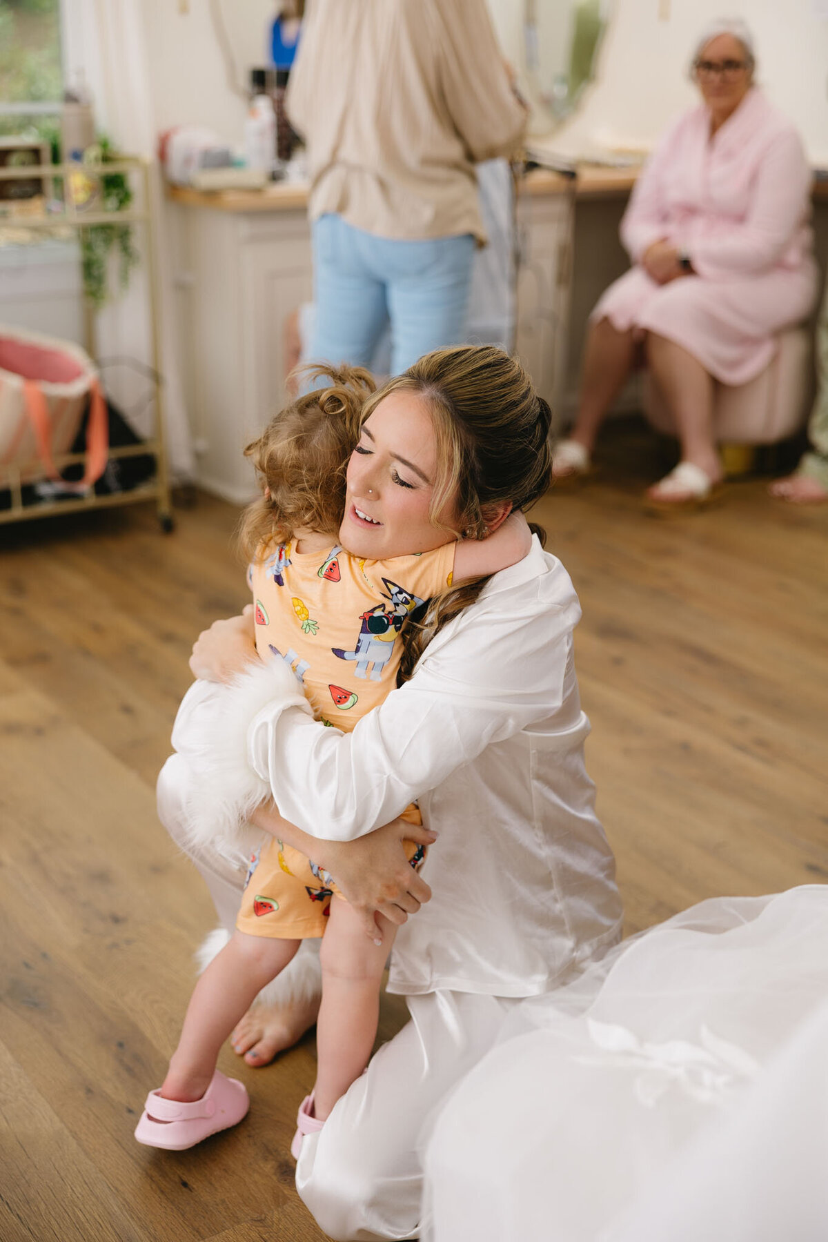 Bride hugging a young child indoors