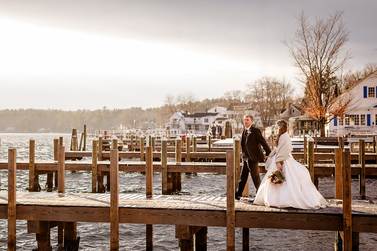 bride and groom walking along docks in winter wedding in Wolfeboro NH