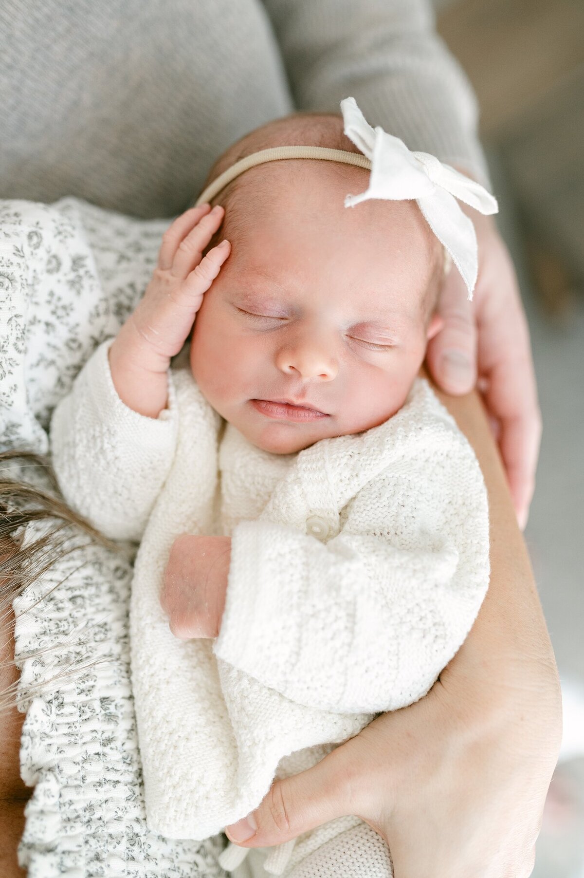 Close up photograph of a newborn baby girl sleeping in her mom's arms