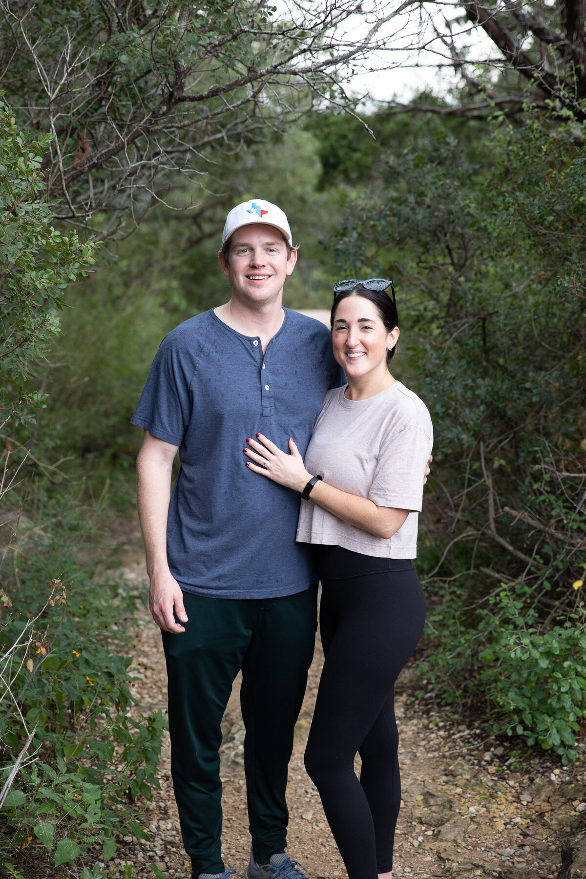 An Austin wedding photographer captures a man and woman standing on a trail in the woods.
