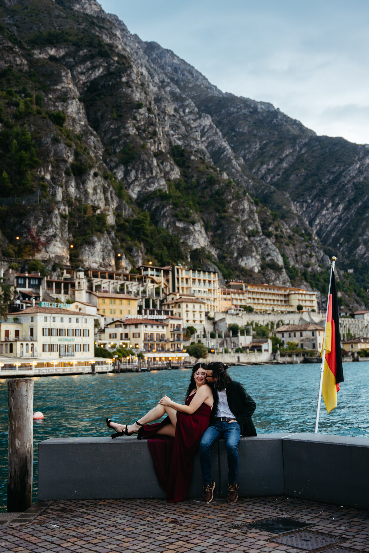 Couple sitting by Lake Garda with mountains behind them