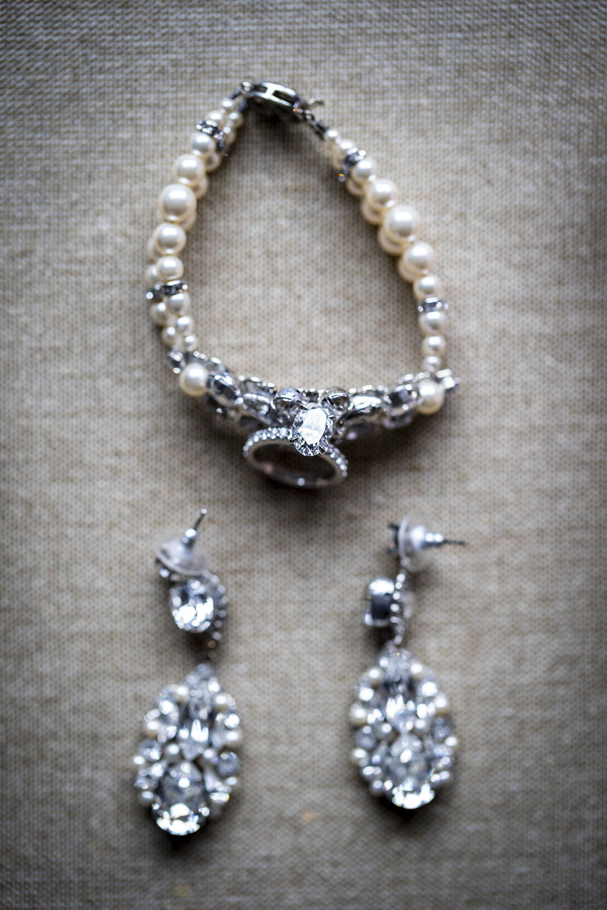 Pearl bracelet and diamond earrings sitting on a mat.