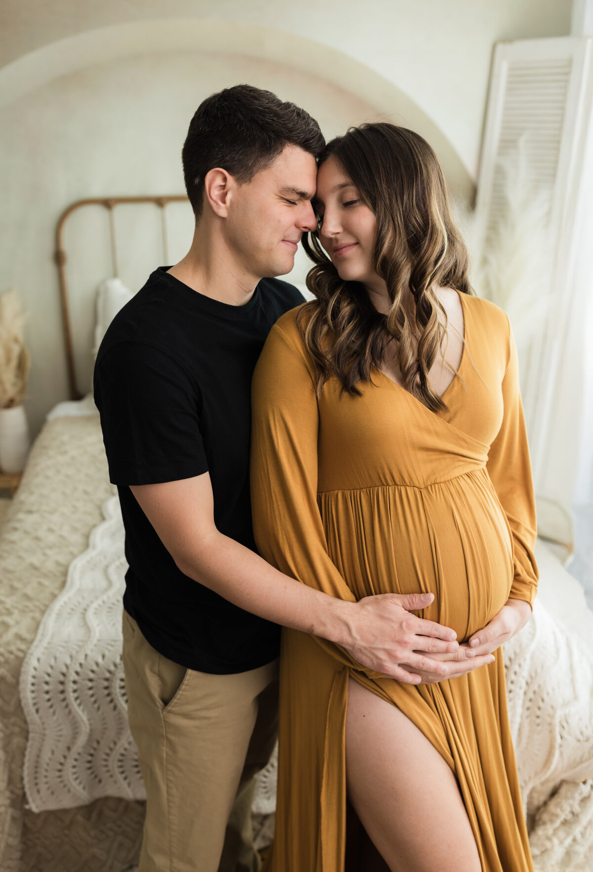 husband and wife  in gold maternity gown holding baby bump for studio maternity photoshoot cleveland maternity photographer
