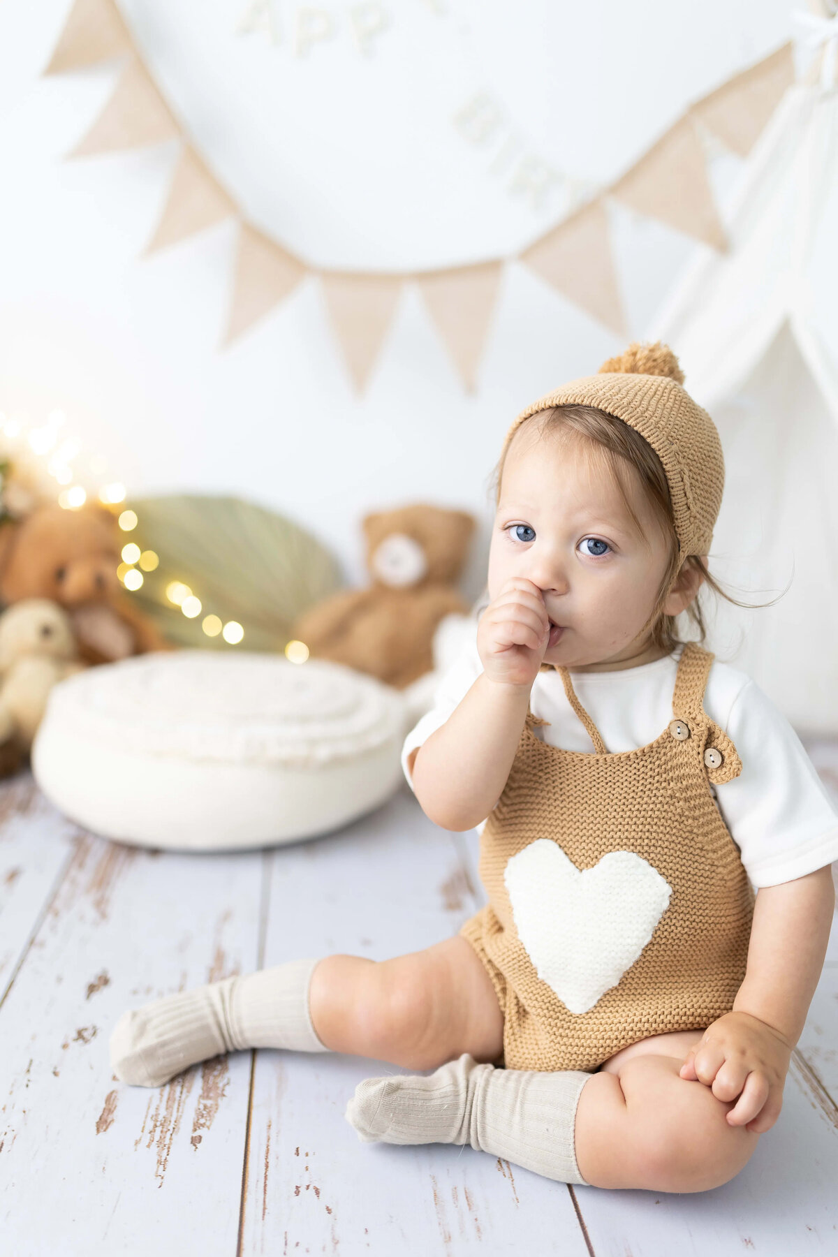 Toddler boy in heart romper sucking thumb - cozy studio milestone session in Maple Grove,MN